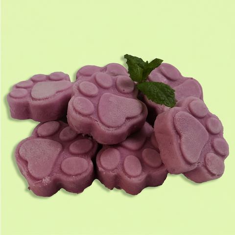Purple paw-shaped dog treats with a sprig of mint on a light green background